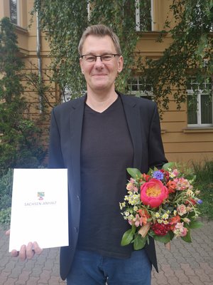 Eike Budinger mit Blumenstrauß und Urkunde