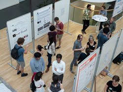 Nachwuchswissenschaftler schauen sich im LIN-Atrium gemeinsam Poster über ihre Arbeit an.