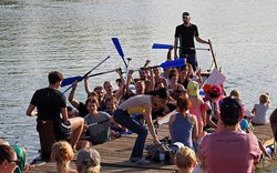 Ein vollbesetztes Drachenboot kommt vom Rennen zurück. Einige jubeln.