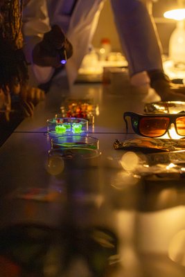 Kinder beobachten fluoreszierende Gummibärchen und lernen dabei, wie Farbstoffe unter besonderem Licht sichtbar werden.