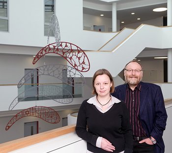 LIN-Geschäftsführung Thekla Thiel und Eckart Gundelfinger stehen im LIN-Atrium. Im Hintergrund ist ein Mobile zu sehen, das Nervenzellen darstellen soll